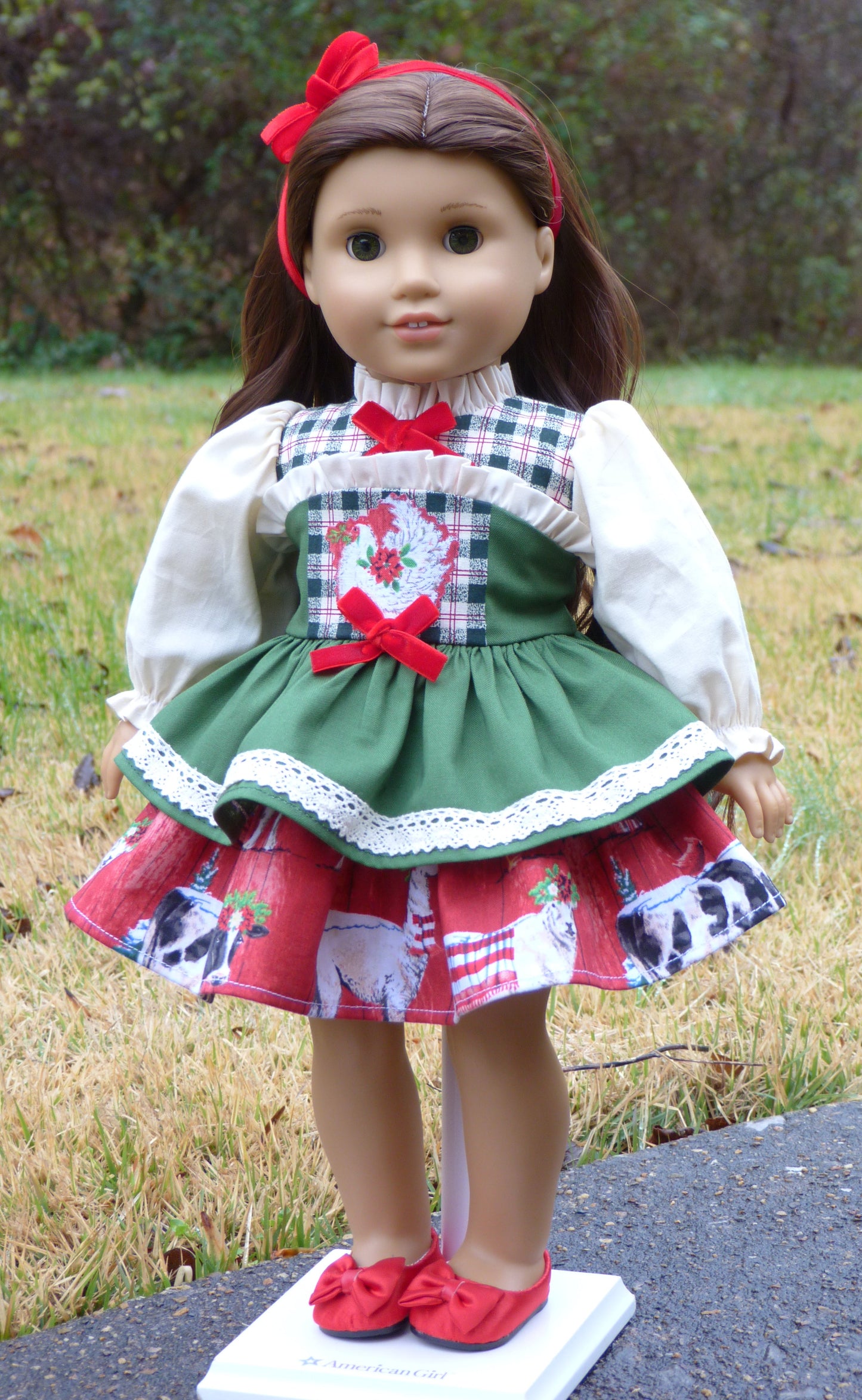 Doll wearing a festive outfit with a green dress and red shoes on a grassy background